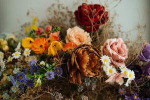 Elegant showy fresh roses and wildflowers picked with beautiful dried flowers and herbs tied up with black cord on grey background